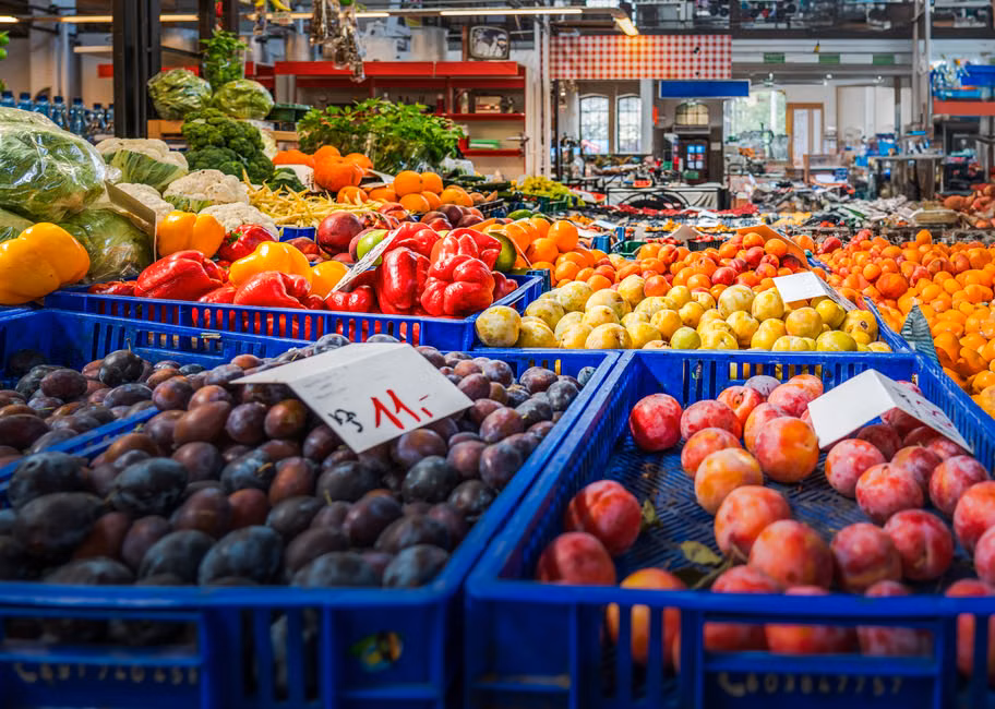 Vibrant fruits and vegetables displayed in crates at an indoor market in Wrocław, Poland.
